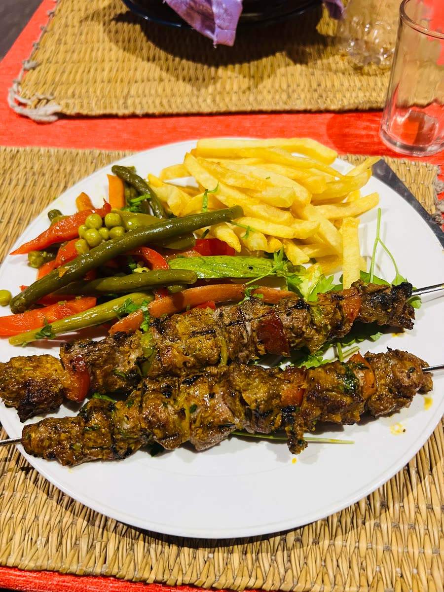 Grilled lamb skewers with mixed vegetables and fries, a staple of Mirleft restaurants
