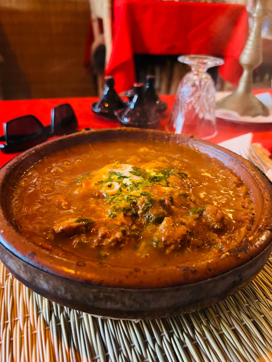 Spicy beef and egg tagine in a clay pot at a Mirleft restaurant — rich tomato and herb sauce